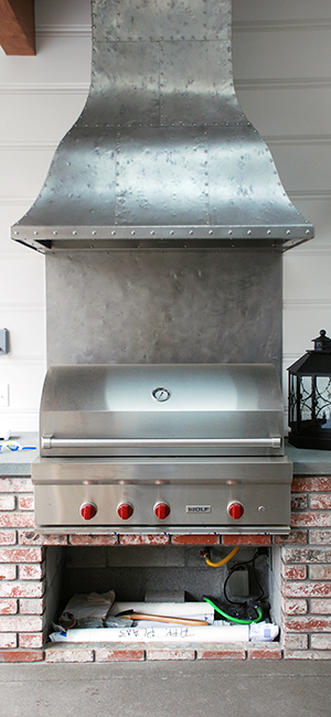 Distressed stainless steel hood installed as a hood for an outdoor BBQ stove.